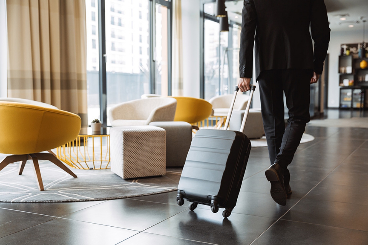 © Drobot Dean - stock.adobe.com Mann zieht Koffer in Hotellobby