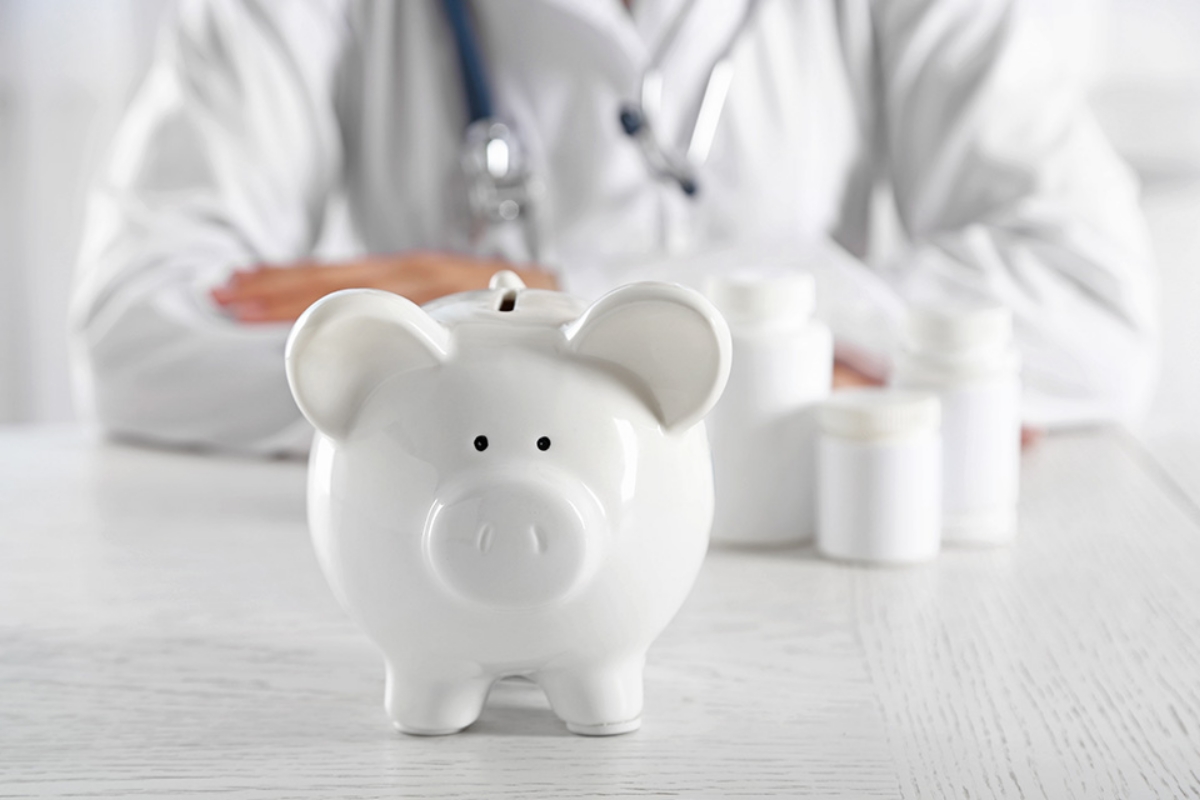 © Africa Studio - stock.adobe.com Arzt sitz hinter Sparschwein